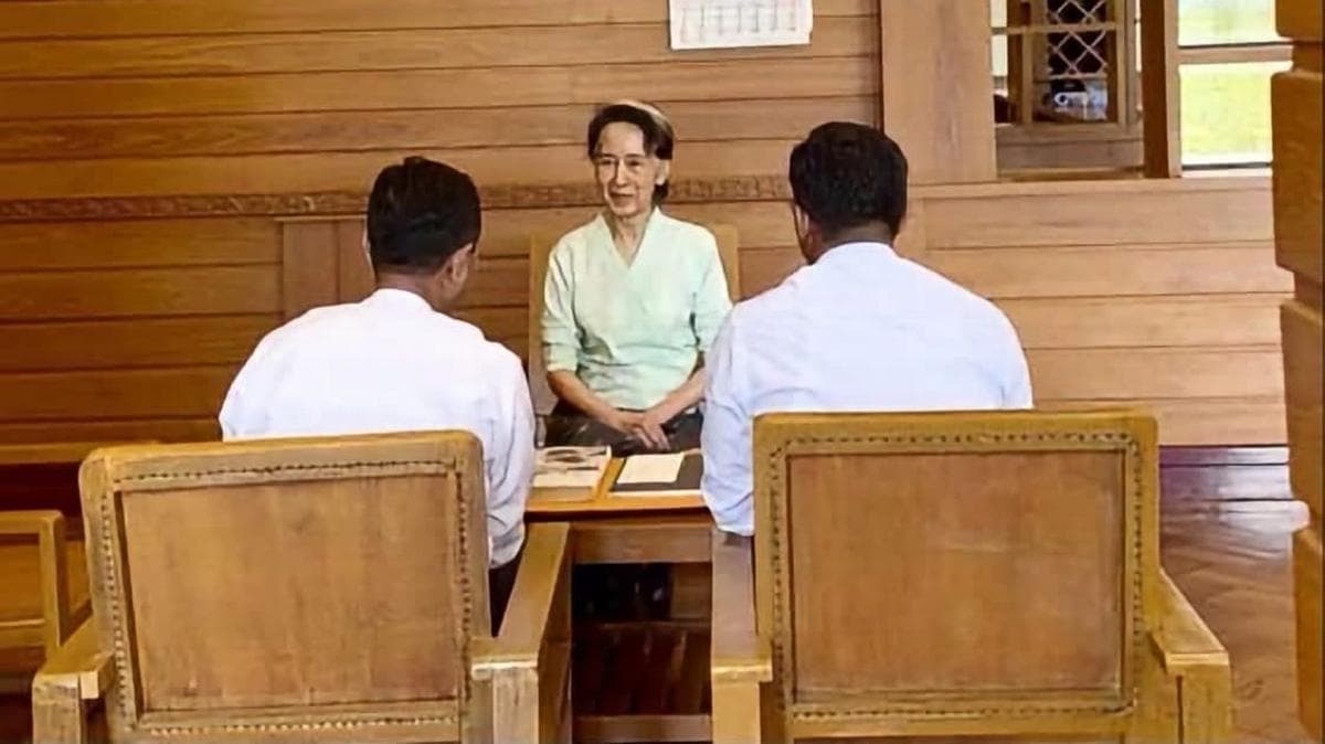 Aung San Suu Kyi, in a pale green Burmese traditional blouse and an olive-coloured skirt, was photographed seated across the table from two men in white shirts.